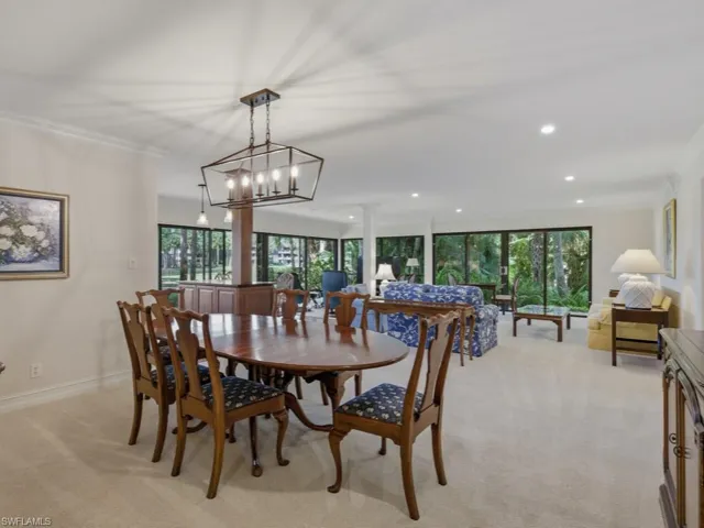Dining area with crown molding, light carpet, and hanging lights