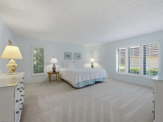 Bedroom with light colored carpet and a textured ceiling