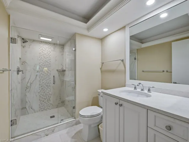 Full bath with recessed lighting, vanity, a marble finish shower, a raised ceiling, and ornamental molding