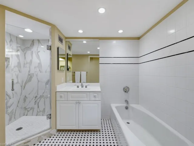 Full bath with vanity, a marble finish shower, a bath, and recessed lighting