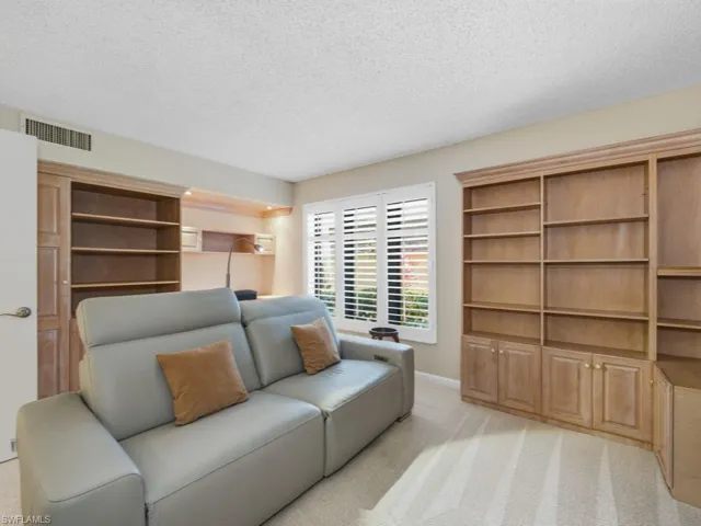 Living area with light colored carpet and a textured ceiling
