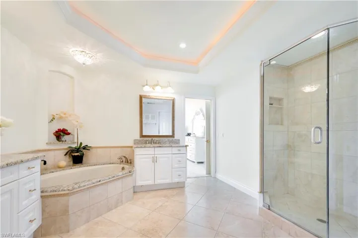 Bathroom with plus walk in shower, tile patterned flooring, ornamental molding, vanity, and a tray ceiling
