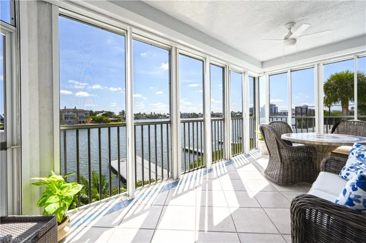 Sunroom / solarium featuring a healthy amount of sunlight, ceiling fan, and a water view