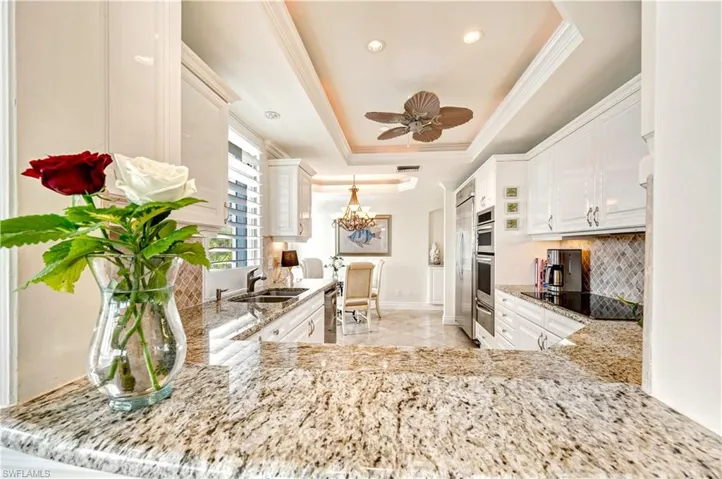 Kitchen with pendant lighting, black electric cooktop, sink, and a tray ceiling