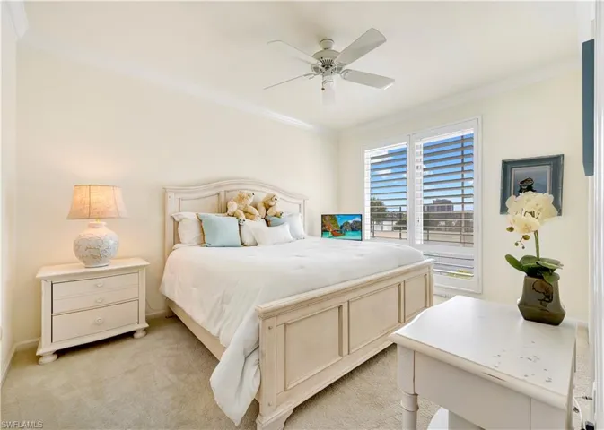 Carpeted bedroom featuring crown molding and ceiling fan