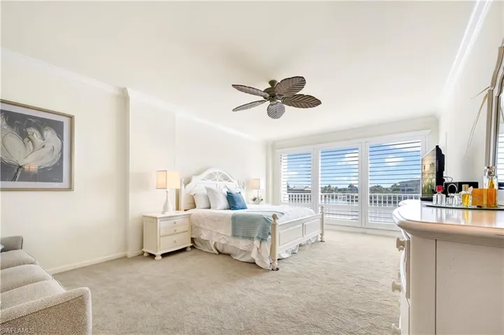 Carpeted bedroom featuring ceiling fan and ornamental molding