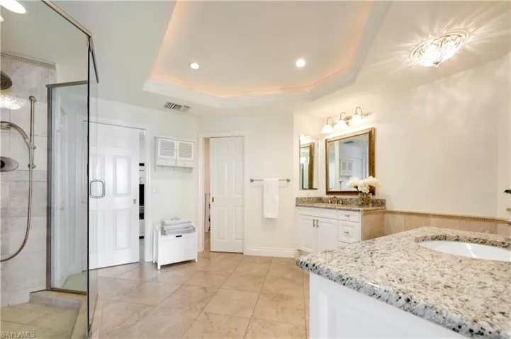 Bathroom featuring crown molding, vanity, a raised ceiling, and a shower with shower door