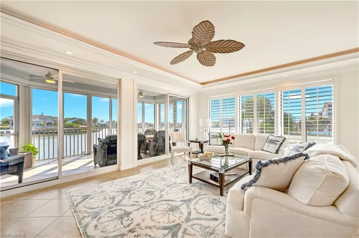 Living room featuring crown molding, a water view, light tile patterned floors, and ceiling fan