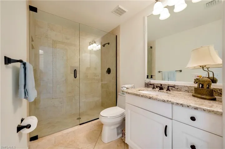 Bathroom with tile patterned flooring, toilet, a shower with door, and vanity