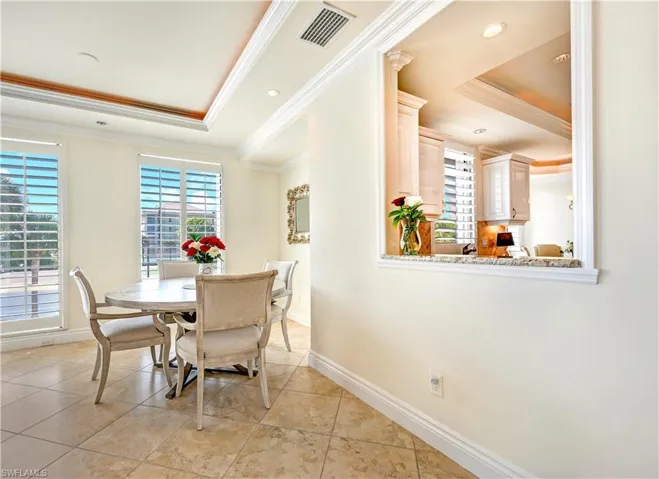 Tiled dining room featuring a tray ceiling and ornamental molding