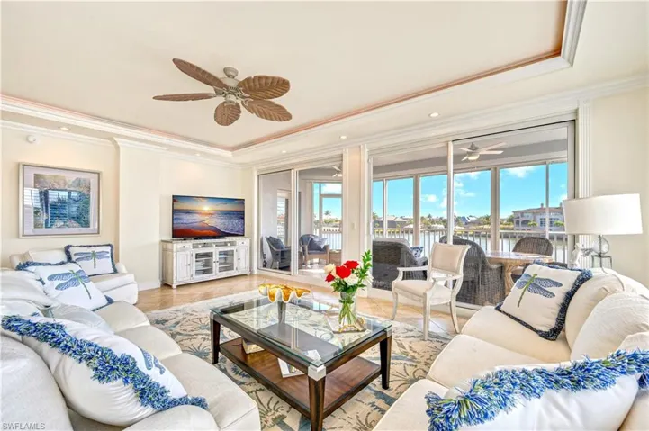 Living room featuring ceiling fan, ornamental molding, and a tray ceiling