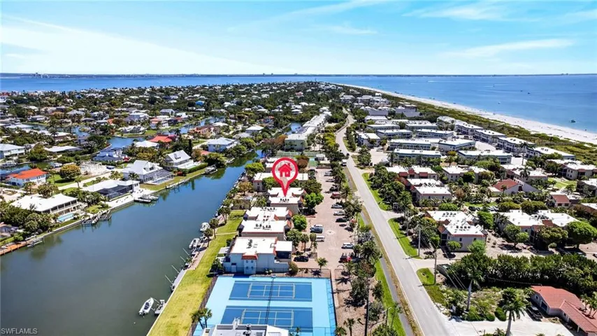 Coastal community featuring waterfront canals, a sandy beach, and a tennis court