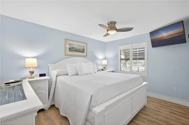 Bedroom featuring light blue walls, wood-finish flooring, and a white bed frame with a slatted footboard