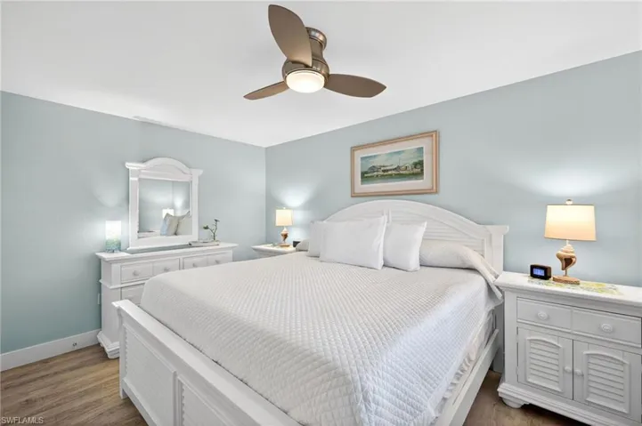 Spacious bedroom with light blue walls and wood-finish flooring