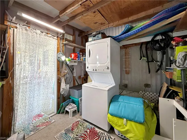 Laundry area with stacked washer / drying machine and light carpet