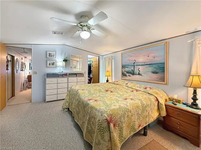 Bedroom featuring vaulted ceiling, a ceiling fan, light colored carpet, and a spacious closet