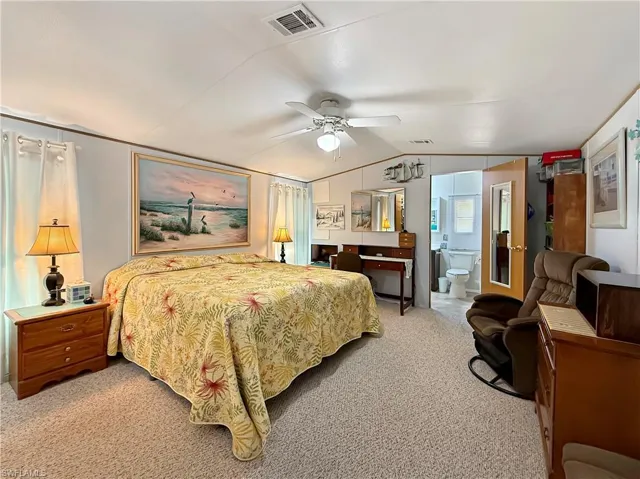 Bedroom with light carpet, ceiling fan, and ensuite bathroom