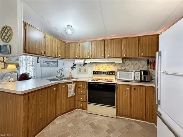 Kitchen with white appliances, light countertops, and a peninsula