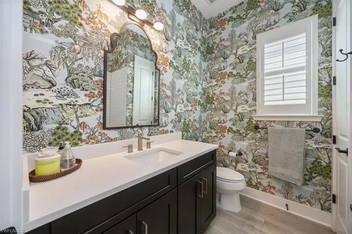Guest bathroom featuring vanity, custom wallpaper, plantation shutters (not shown tub with subway tile walls)
