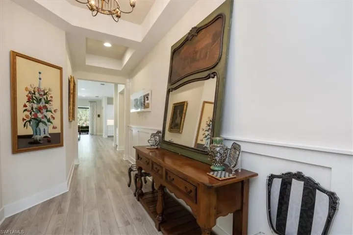 Foyer entrance has tray ceiling, wainscoting and custom lighting. From the foyer, you can see straight through to the pool area