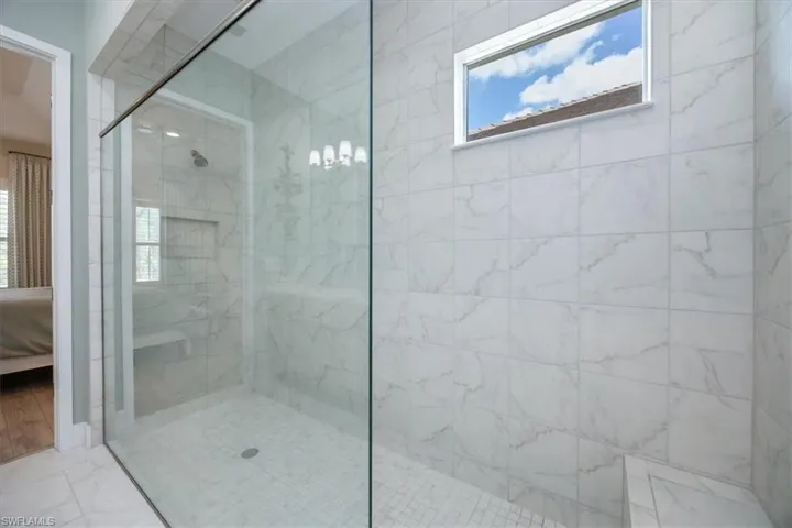Primary bathroom featuring huge walk in shower with frameless shower door, bench and transom window