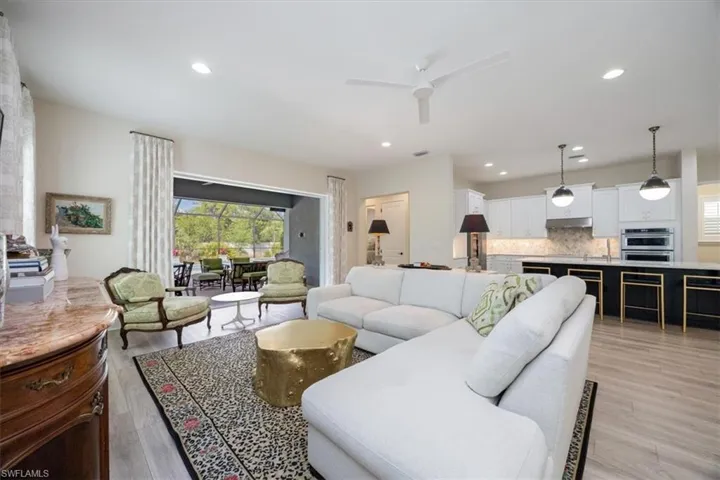 Living room with recessed lighting, light wood-type flooring, and ceiling fan open up with disappearing pocket sliders to the outdoor area