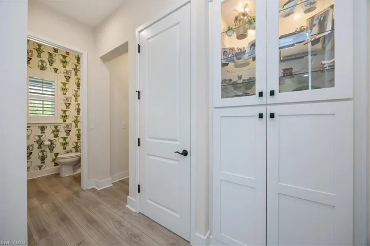 Hallway to half bath and Primary bedroom has a custom built in with glass doors on the top