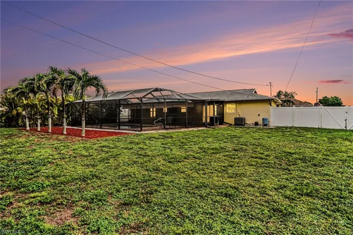 Expansive grassy lawn with a screened-in pool area featuring a paved deck and integrated steps