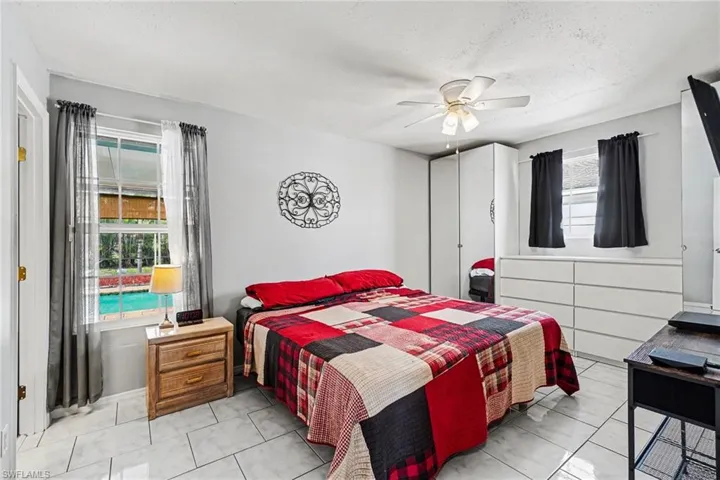 Bedroom featuring tiled flooring, a ceiling fan with integrated lighting, and two windows
