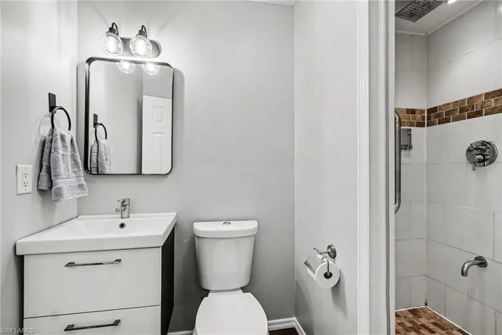 Bathroom featuring a white vanity with integrated sink, rectangular mirror with rounded corners, and a contemporary vanity light fixture