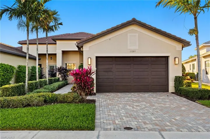 View of front of property featuring a garage, decorative driveway, a tile roof, and stucco siding