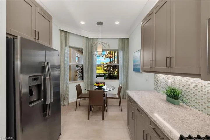 Kitchen featuring hanging light fixtures, gray cabinets, backsplash, and stainless steel fridge with ice dispenser