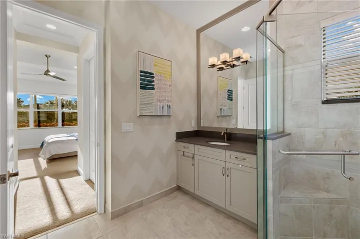 Ensuite bathroom with ensuite bath, a shower stall, baseboards, and vanity