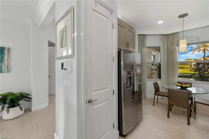 Kitchen featuring stainless steel refrigerator with ice dispenser, light tile patterned floors, gray cabinets, ornamental molding, and baseboards