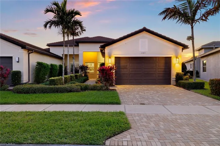 View of front of home featuring a garage, decorative driveway, and stucco siding