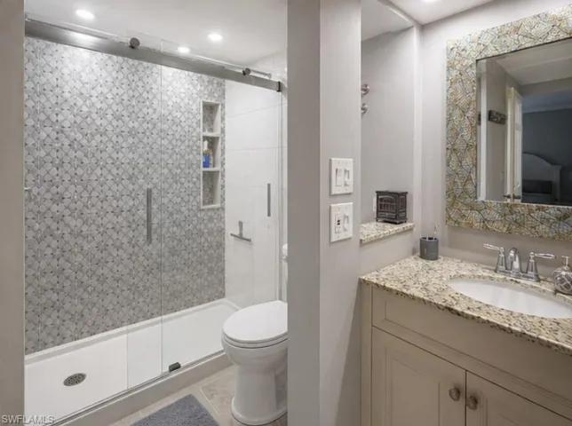 Bathroom featuring a walk-in shower with patterned tile, glass enclosure, and recessed shelving