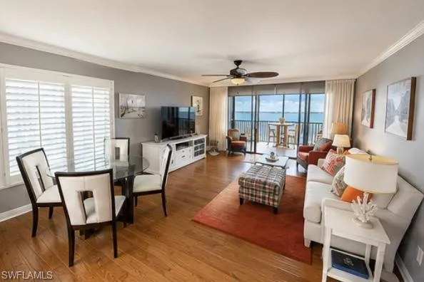 Open concept living area featuring wood-finish flooring, crown molding, and a built-in media console