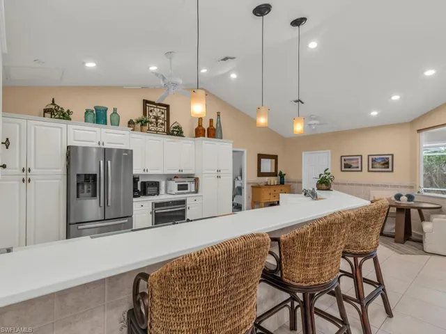 Kitchen with white cabinetry, appliances with stainless steel finishes, a breakfast bar, and pendant lighting