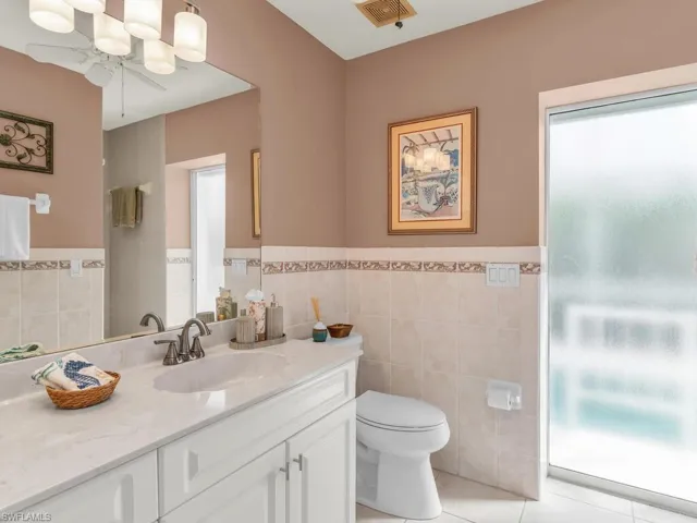 Bathroom with tile walls, vanity, toilet, and tile patterned floors