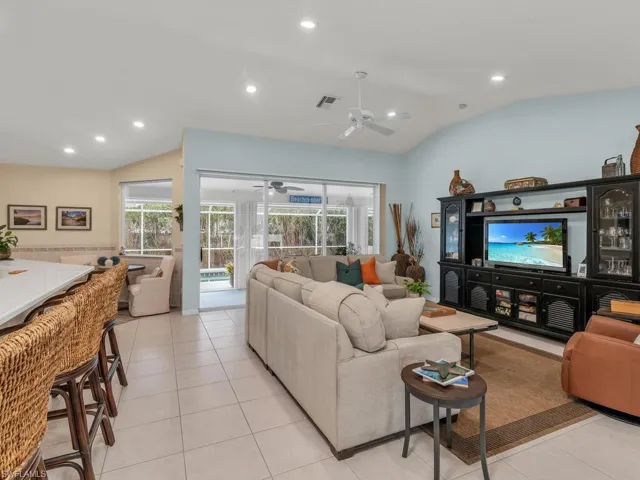 Tiled living room with ceiling fan and lofted ceiling