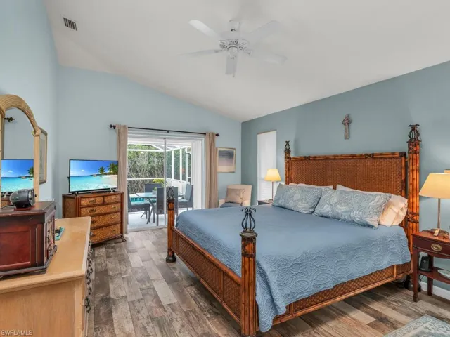 Bedroom with ceiling fan, access to outside, dark hardwood / wood-style floors, and vaulted ceiling