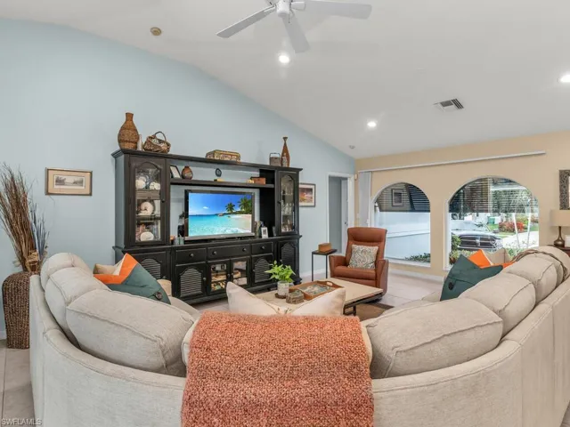 Living room featuring light tile patterned floors, ceiling fan, and vaulted ceiling