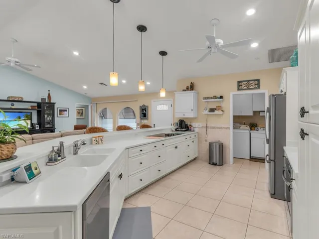 Kitchen featuring hanging light fixtures, white cabinetry, stainless steel appliances, and washing machine and clothes dryer