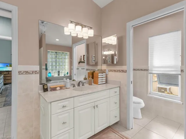 Bathroom featuring tile patterned floors, toilet, tile walls, and vanity
