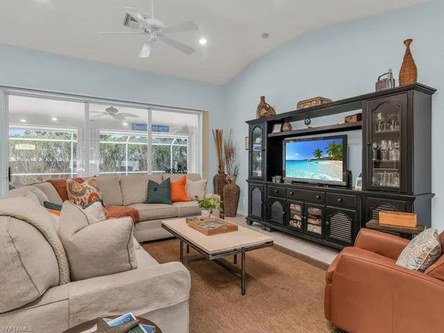 Tiled living room with ceiling fan and lofted ceiling