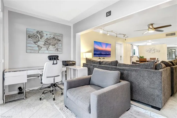 Living area featuring a ceiling fan, light marble finish flooring, a desk, and rail lighting