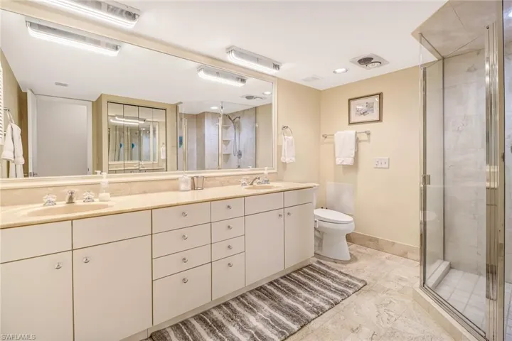 Bathroom with a stall shower, double vanity, and recessed lighting