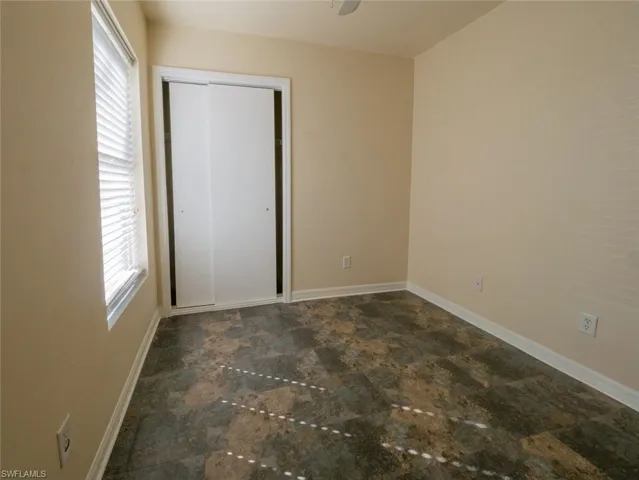 Unfurnished bedroom with a closet, multiple windows, and ceiling fan