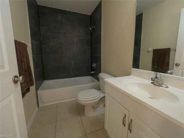 Full bathroom featuring tile patterned floors, vanity, tiled shower / bath combo, and toilet