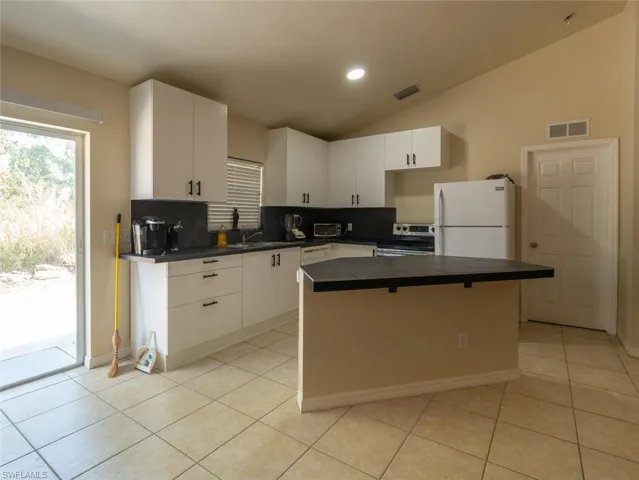 Kitchen featuring a center island, white fridge, lofted ceiling, and backsplash